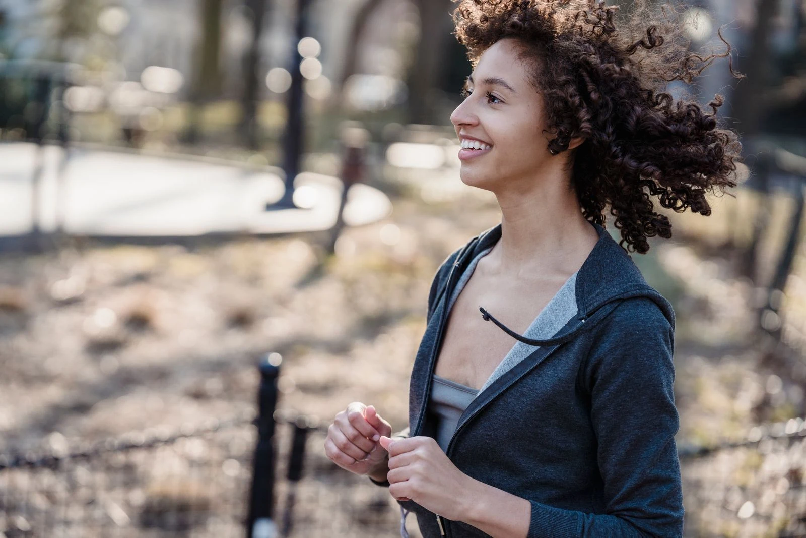 A FITMETABOLIC member smiling mid-run in the park