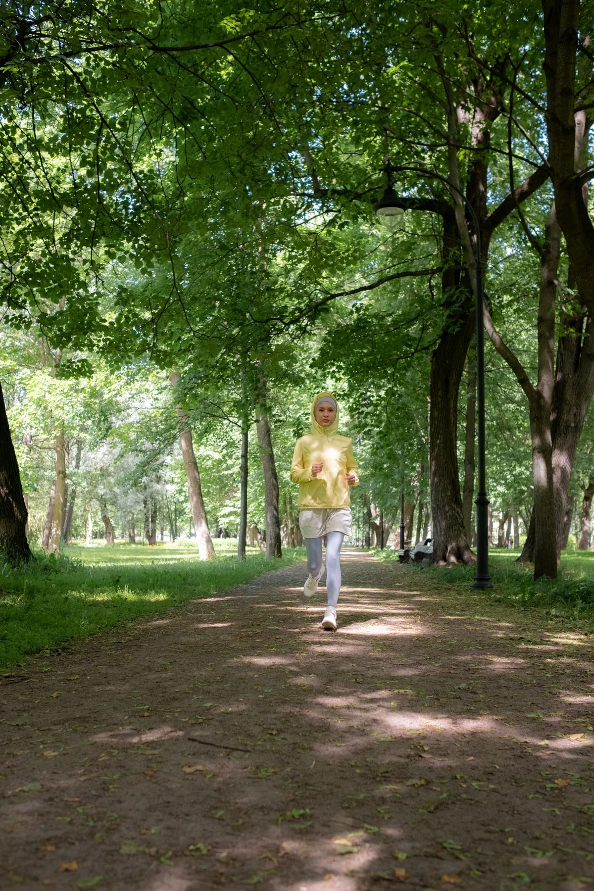 FITMETABOLIC member out for a run on a sunlit tree-lined park path